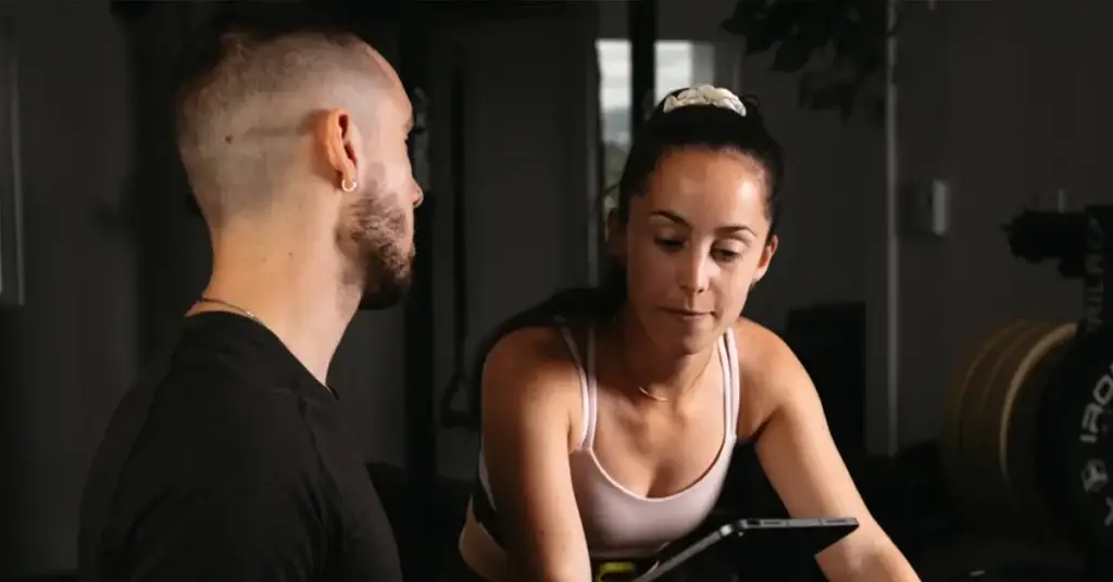 Émile Fortier, kinésiologue au Studio Sportif, en consultation avec une cliente sur tablette dans le studio