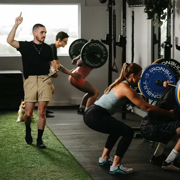 Émile Fortier dirigeant une séance de groupe avec exercices de squat à la barre dans son studio